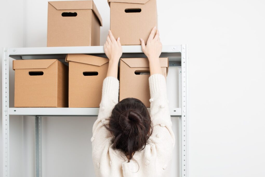 women placing boxes on a metal storage rack