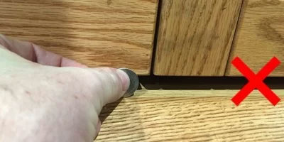 person holding a coin up to a bookcase door gap