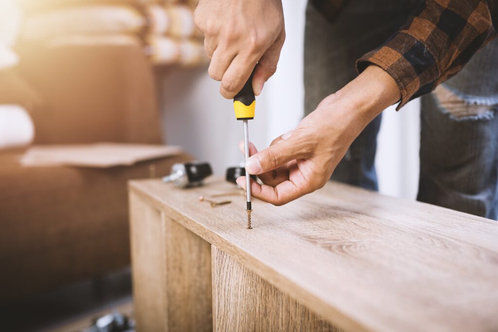 handy man screwing in a screw to the side of a boocase