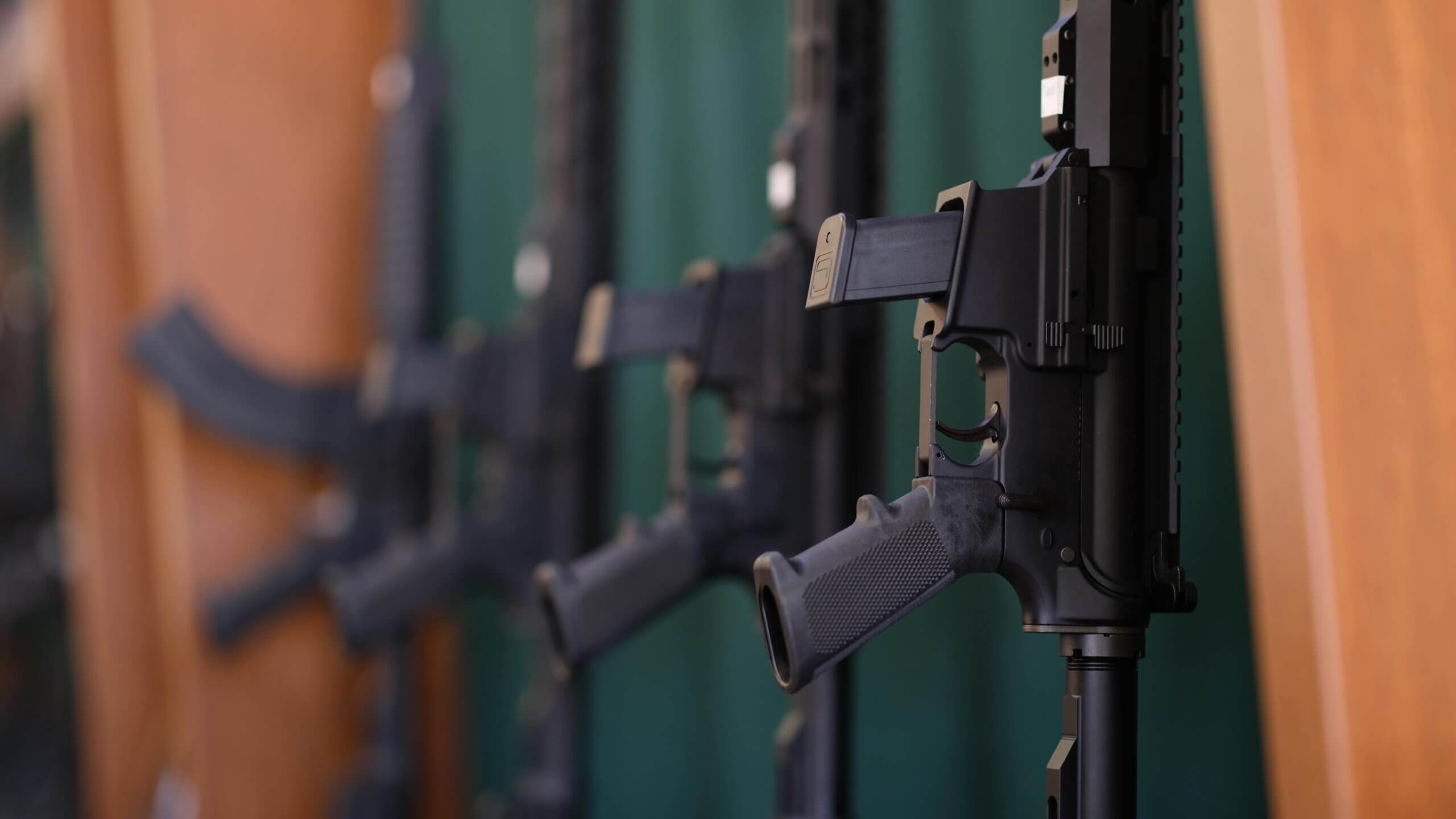 Row of black rifles displayed vertically on a rack, safe gun storage.