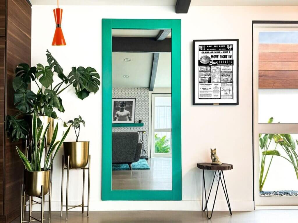 A full-length diy mirror hidden door with a bold green frame conceals a tiki bar.